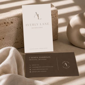 May include: A vertical off-white business card with the logo AL and text AVERY LANE INTERIORS, and a horizontal dark brown business card with the name LAUREN HARRISON, PRINCIPAL DESIGNER, contact details, and a circular AL logo.