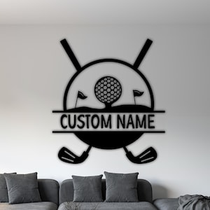 Puede incluir: Arte de pared de metal negro con temática de golf. El diseño presenta una pelota de golf, palos de golf cruzados, banderas y el texto "CUSTOM NAME". Esta pieza decorativa es adecuada para exhibir en interiores.