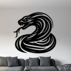 May include: A large, black metal wall art piece showing a stylized snake in a coiled pose. The snake's head is raised, with its tongue extended. The artwork is mounted on a white wall above a grey sofa, adding a modern touch to the room.