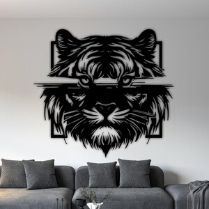 May include: Black metal wall art of a tiger's face. The artwork is a stylized representation of a tiger's head, with detailed fur and facial features. The piece is mounted on a white wall above a grey sofa.