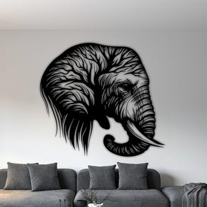 May include: A large, black metal elephant head wall art. The elephant's head is depicted in profile, with intricate details in the trunk, tusks, and ear. The artwork is mounted on a white wall above a gray sofa, creating a striking contrast.
