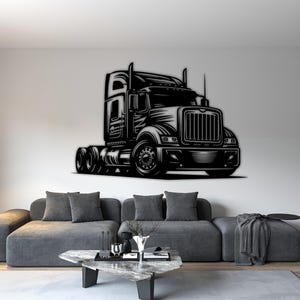 May include: Black and white metal wall art of a semi-truck. The artwork is mounted on a white wall above a gray sofa. The truck features detailed grill, wheels, and cab design, creating a bold, industrial aesthetic.