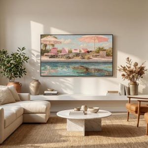 A serene view of a modern minimalist living room where natural morning light illuminates a textured wall. Above a white built-in shelf, the funny crocodile pool art is displayed on a Samsung Frame TV, adding a splash of color to the neutral interior. The scene evokes a sense of calm and high-end coastal living with a touch of whimsical humor. Redefine your technology with this artistic summer background—click to download and enjoy the view.