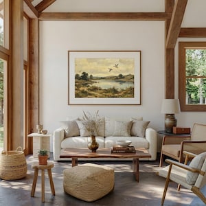 [Country Home Decor] vintage wildlife painting shown in a large-scale format in a sun-drenched, open-concept living room with high ceilings and exposed wooden beams. The lake landscape art is the focal point above a white textured sofa, surrounded by rattan furniture and natural light. This grand lifestyle scene demonstrates the versatility of our printable digital art for oversized statement pieces — bring calm artistry to your walls instantly.