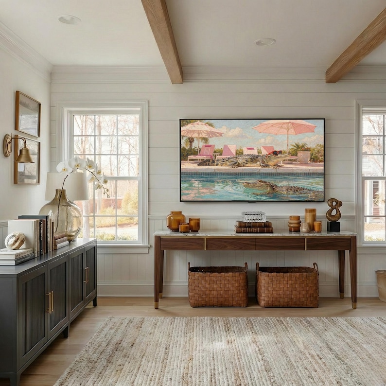 A cinematic view of a bright, airy living room with white shiplap walls and a wooden console table. Centered on the wall, a Samsung Frame TV displays the funny Palm Springs crocodile art, perfectly complementing the mid-century modern aesthetic. The natural light highlights the painting’s vibrant pinks and turquoise blues, creating a cheerful atmosphere. Elevate your home’s personality today—click to download this high-resolution digital art instantly.
