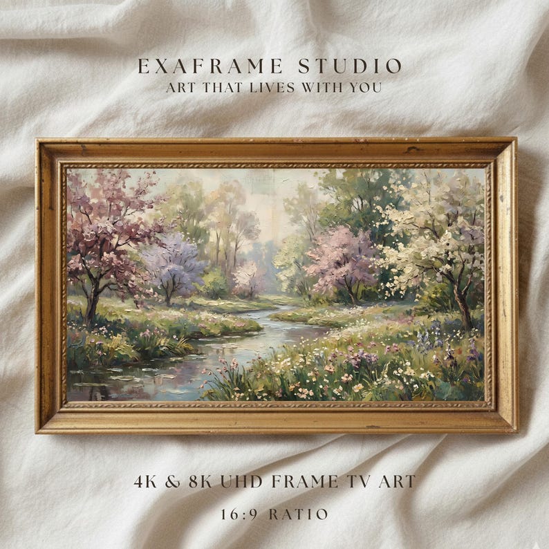 A beautifully framed vintage spring landscape painting presented inside an antique carved gold frame resting against a soft textured linen textile background. The impressionist brushstrokes and delicate floral elements create an heirloom-quality aesthetic. Perfect for classic cottagecore styling, this artwork brings timeless elegance to any interior. Click to download this exquisite fine art piece.