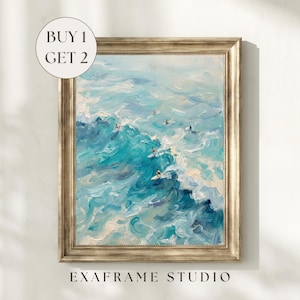May include: An oil painting of ocean waves in shades of blue and turquoise, with several surfers riding the waves. The artwork is in a gold-colored frame. The text "BUY 1 GET 2" is in a white circle in the upper left corner. The text "EXAFRAME STUDIO" is at the bottom.