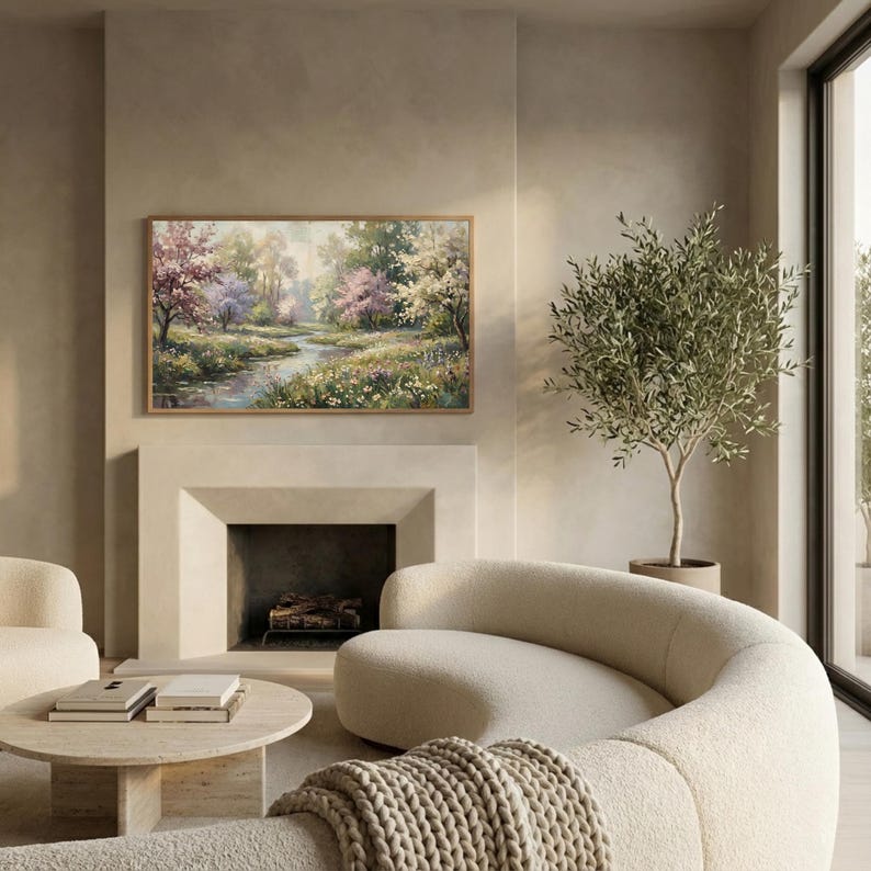 Modern neutral living room mockup featuring a curved beige sofa and olive tree. The Samsung Frame TV displays a romantic spring oil painting with blooming trees and a river. Demonstrates how vintage art complements modern heritage and warm minimalist interiors. Creates a calm and sophisticated atmosphere. Shop this elegant digital decor for your home.