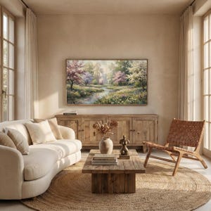A cozy, sunlit rustic living room showcasing a muted green meadow spring artwork on a television screen mounted above a weathered wooden sideboard. A natural jute area rug, comfortable cream sofa, and leather accent chair complete the warm organic atmosphere. Bring the serene beauty of the outdoors into your home. Click to acquire this high-resolution digital screensaver.