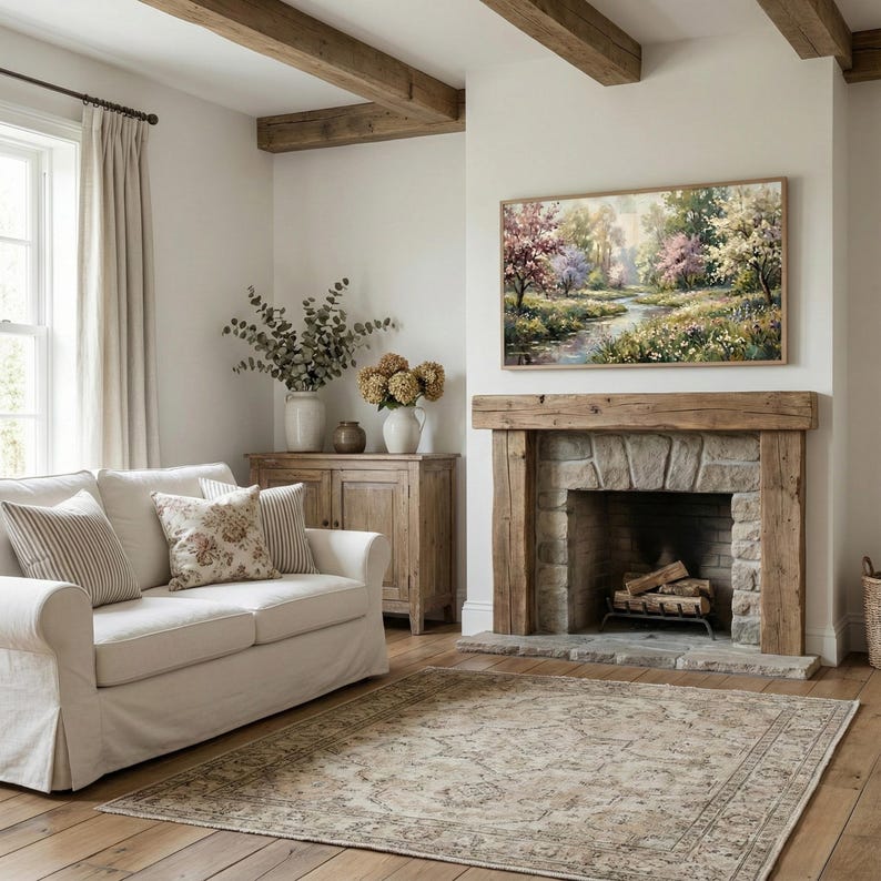 Rustic farmhouse living room scene with a stone fireplace and wooden beams. The Samsung Frame TV displays a muted green meadow and blooming tree painting. The artwork enhances the cozy, country cottage atmosphere. Perfect for spring farmhouse decor and nature-inspired interiors. Bring the beauty of the outdoors inside with this digital download.