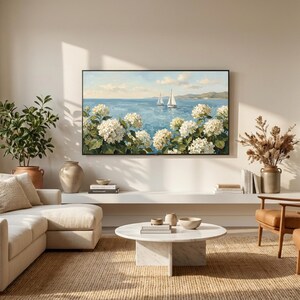 A serene view of a sun-drenched modern living room where a Samsung Frame TV displays the white hydrangea and sailboat art. The space features a clean white sofa and a minimalist round coffee table, reflecting the airy coastal granddaughter lifestyle. The artwork brings a refreshing breeze and sophisticated charm to the bright, neutral interior. Ideal for seasonal summer updates—click to download and refresh your home’s energy today.
