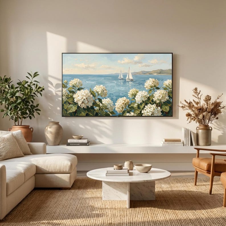 A serene view of a sun-drenched modern living room where a Samsung Frame TV displays the white hydrangea and sailboat art. The space features a clean white sofa and a minimalist round coffee table, reflecting the airy coastal granddaughter lifestyle. The artwork brings a refreshing breeze and sophisticated charm to the bright, neutral interior. Ideal for seasonal summer updates—click to download and refresh your home’s energy today.