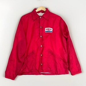 May include: A bright red nylon coach jacket featuring a classic collar, long sleeves, and a front snap-button closure. A white rectangular patch with the red and blue Exxon logo is stitched onto the left chest area. The jacket has two side pockets.