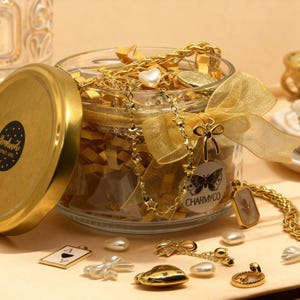May include: A clear glass jar with a gold lid and a gold ribbon bow, filled with gold-toned jewelry including a star-link chain and a heart charm. A circular sticker on the jar features a butterfly illustration and the text CHARMYCO.