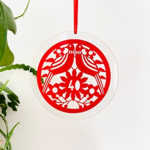 Könnte beinhalten: Roter Papierschnitt-Anhänger mit zwei Vögeln und einem floralen Design. Die Zahl 40 befindet sich in der Mitte des Anhängers.