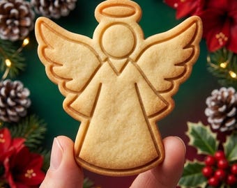 May include: A light tan, angel-shaped cookie with a smooth surface and embossed outlines of wings, a halo, and a dress. The cookie features a clean, minimalist design with defined edges, showcasing a uniform golden-brown baked texture throughout.