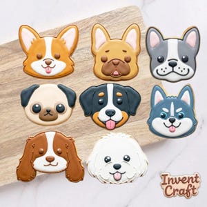 May include: Eight dog-shaped sugar cookies with colorful icing, featuring various breeds including a corgi, pug, and husky. The cookies are arranged in a grid pattern. A small, separate cookie in the bottom right corner displays the text Invent Craft.