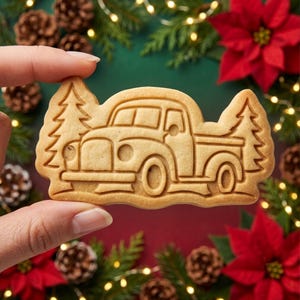 Peut inclure: Un biscuit cuit au four, de couleur brun clair, en forme de camionnette vintage avec un sapin de chaque côté. Le biscuit présente des détails en relief de la carrosserie, des roues, des fenêtres et des silhouettes texturées des sapins.
