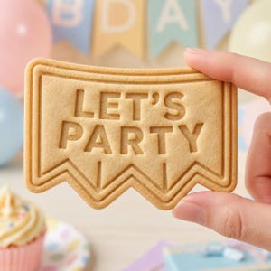 May include: A light tan, rectangular-shaped cookie shaped like a pennant flag with a zigzag bottom edge. The cookie features the embossed text LET'S PARTY in the center, surrounded by a raised border that follows the shape of the cookie.