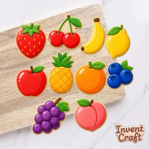 May include: A collection of ten fruit-shaped cookies featuring a red strawberry, two red cherries, a yellow banana, a yellow lemon, a red apple, a yellow pineapple, an orange, three blue blueberries, purple grapes, and a pink peach.