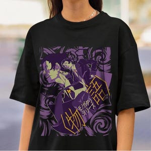 May include: Black t-shirt featuring a purple and white anime-style graphic. The graphic includes two figures, Japanese text, and swirling patterns. The design is centered on the front of the shirt.