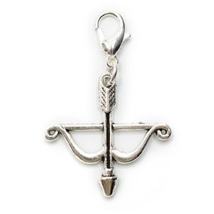 Può includere: Un ciondolo color argento con un design a forma di arco e freccia, con un moschettone per un facile fissaggio. La freccia è centrata sull'arco e il ciondolo ha un'estetica vintage dettagliata. Perfetto per la creazione di gioielli o come pendente.