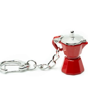 Könnte beinhalten: Ein roter Schlüsselanhänger aus Metall in Form einer traditionellen italienischen Kaffeekanne, oder Moka-Kanne. Der Schlüsselanhänger hat einen silbernen Deckel und eine silberne Kette.