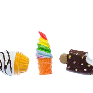 Könnte beinhalten: Drei Miniatur-Eiswaffeln, eine mit Regenbogen-Swirl, eine mit weiß-braunem Swirl und ein Schokoladeneis am Stiel mit weißen und rosa Streuseln.