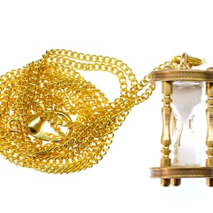 May include: A gold chain necklace with a gold hourglass pendant. The hourglass is filled with white sand and has a clear glass bulb.