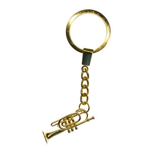 May include: A gold-colored keychain featuring a miniature trumpet charm attached to a gold chain and a gold ring.