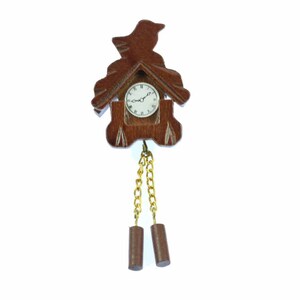 Könnte beinhalten: Eine Holzkuckucksuhr mit einem Vogel oben und einer goldenen Kette mit zwei braunen Gewichten. Das Zifferblatt der Uhr hat römische Ziffern und einen weißen Hintergrund.