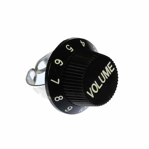 以下が含まれることがあります： 白い数字と「VOLUME」という文字が印刷された黒いボリュームノブです。