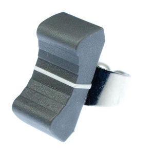 Puede incluir: Una perilla de plástico gris con una franja blanca y un anillo de metal plateado.