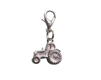 May include: Silver charm of a tractor with a silver clip attached.