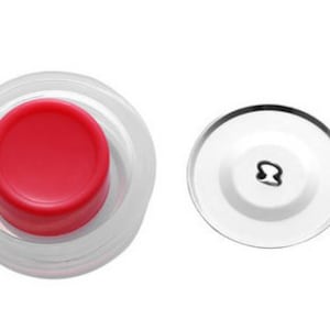 May include: A clear plastic bottle stopper with a red push-down button and a separate clear plastic lid with a metal hook.