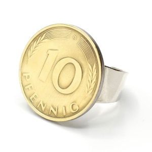 May include: A gold-colored ring with a 10 Pfennig coin from Germany as the face. The coin has a wheat design around the edge and the number 10 in the center.