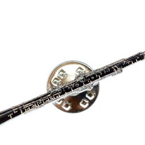 Peut inclure: Épinglette argentée représentant un hautbois noir et argenté. Le hautbois est détaillé, avec ses clés et son corps. L'épinglette est fixée à un support rond argenté, idéale pour les musiciens.