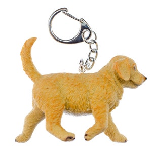 Può includere: Un portachiavi a forma di cucciolo golden retriever con un anello portachiavi argentato. Il cucciolo cammina con la coda che scodinzola.