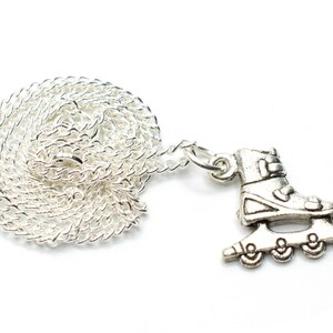 May include: A silver-colored necklace featuring a roller skate charm. The charm is a detailed miniature of a roller skate. The chain is a delicate, coiled design. The background is plain white.