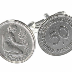 May include: A pair of silver cufflinks featuring a vintage German 50 Pfennig coin. One cufflink shows the front of the coin with a woman planting a tree, and the other cufflink shows the back of the coin with the denomination "50 Pfennig" and the text "Bundesrepublik Deutschland".