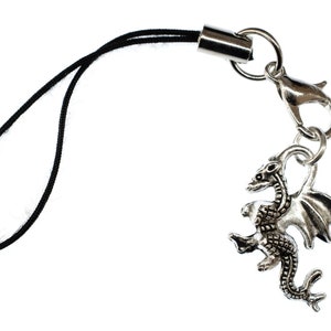 May include: A silver dragon charm attached to a black string phone charm.