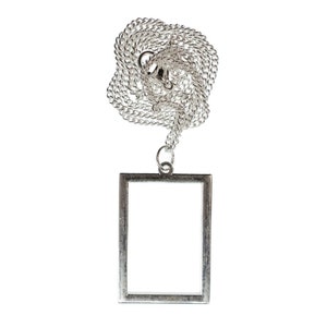 May include: A silver chain necklace with a rectangular pendant. The pendant is a simple frame with a smooth, polished finish.