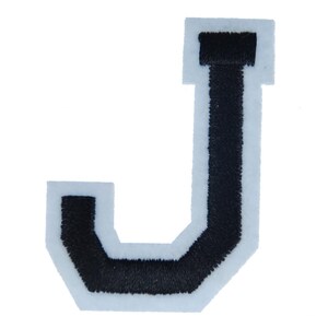 Könnte beinhalten: Ein schwarzer, gestickter Buchstabe "J" Aufnäher mit weißem Rand. Der Buchstabe ist in einem fetten Blockstil gehalten, geeignet für das Aufnähen auf Kleidung oder Accessoires. Der Aufnäher ist vor weißem Hintergrund isoliert.