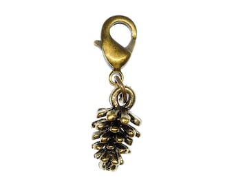 May include: A gold-toned metal charm in the shape of a pine cone with a lobster clasp attached.