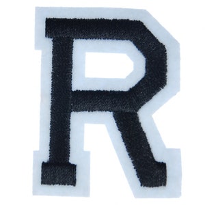 May include: Black felt letter R with white outline. The letter is embroidered and has a slightly raised texture.