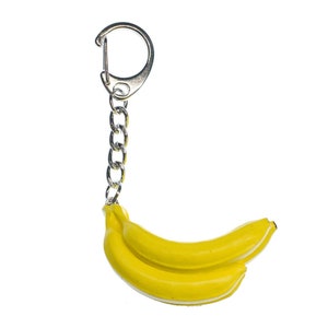 May include: A yellow banana keychain with a silver chain and a silver ring.