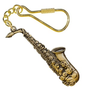 Könnte beinhalten: Ein bronzefarbener Saxophon-Schlüsselanhänger mit einer goldfarbenen Kette und einem Verschluss. Das Saxophon ist sehr detailliert, mit sichtbaren Klappen und einem Schalltrichter. Der Schlüsselanhänger ist wahrscheinlich aus Metall und zum Befestigen an Schlüsseln oder einer Tasche gedacht.