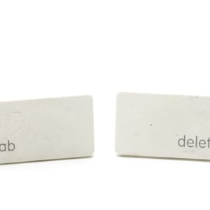 Puede incluir: Dos teclas rectangulares blancas con las palabras "tab" y "eliminar" impresas en ellas.