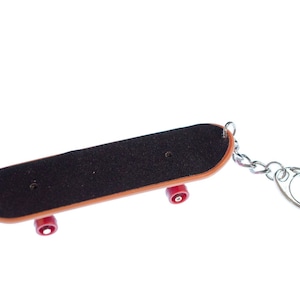 May include: A small, brown skateboard keychain with red wheels and a silver metal chain.