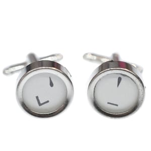 May include: A pair of silver cufflinks featuring typewriter keys. The keys are white with black lettering. The left cufflink has the letter 'L' on it. The right cufflink has a hyphen on it.